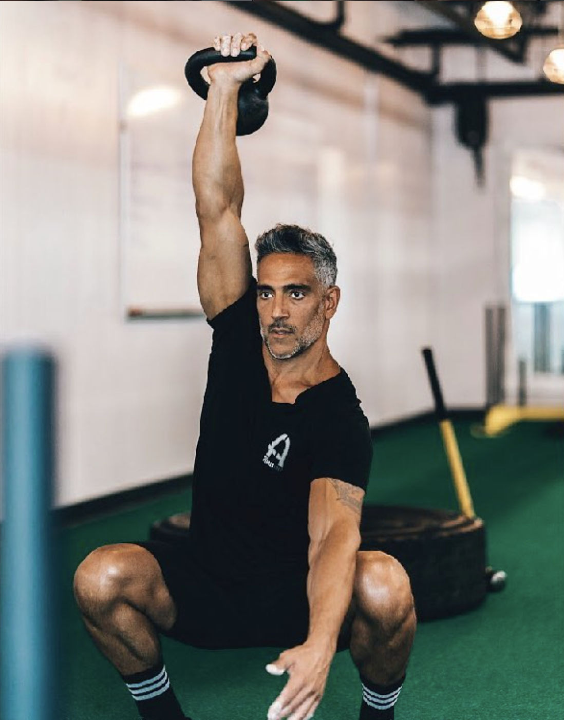 Darren Oropallo performing a single-arm overhead kettlebell squat at his Saratoga Springs training studio